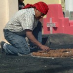A Mayan man prepares an elaborate miniature pyre for burning in the Chichicastenango Cemetery