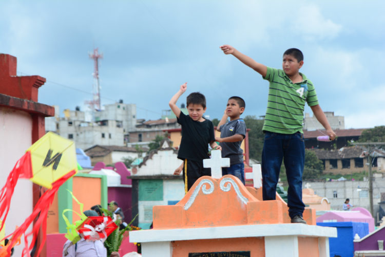 Boys fly kites while standing atop a tomb on All Saints Day in Chichicastenango, Nov. 1, 2016.