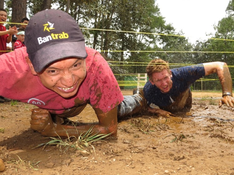 A youth leader and an ORU student take on the mud challenge during the Cords Rally Day at ASELSI's youth leader training activity.