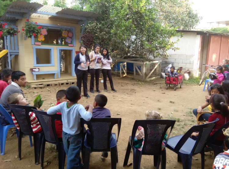 The three volunteers explaining a handicraft project to help the kids remember the story of Creation.