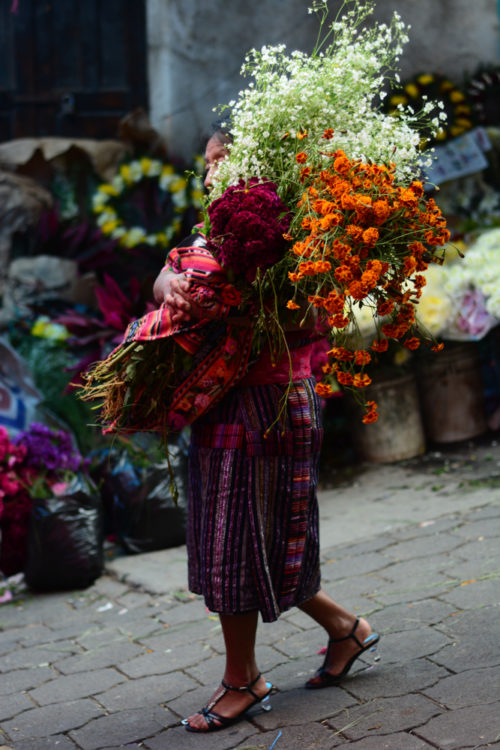 A woman carries flowers to the cemetery on All Saints Day, Nov. 1, 2016 in Chichicastenango, Guatemala.